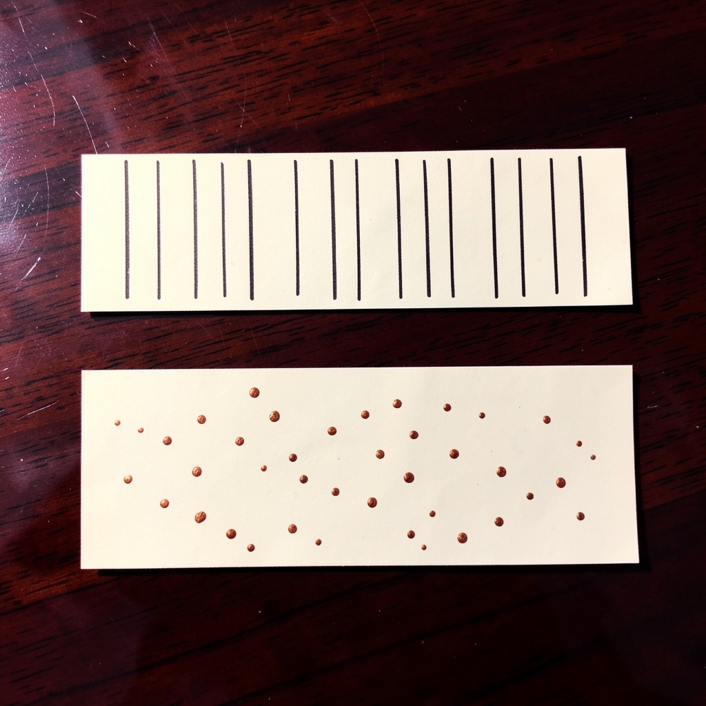 Two horizontal ivory strips on a lacquered table, one with bars and one with small copper marks